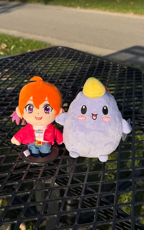 The plush crew sitting side by side on a sunny park bench
