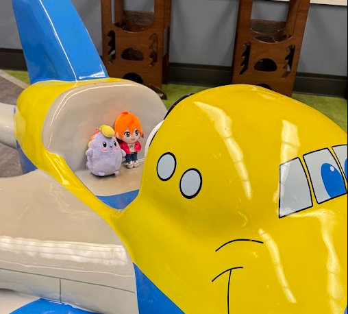 Plushies sitting inside a yellow toy airplane cockpit ride